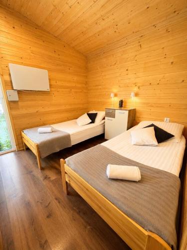two beds in a room with wooden walls at Sarzynówka pod Świerkiem in Krasnobród