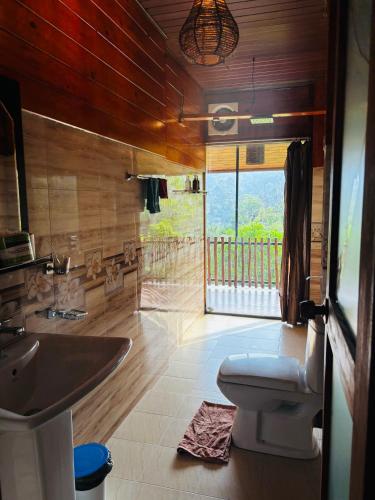 a bathroom with a sink and a toilet and a window at Ella Wood Cabin in Ella