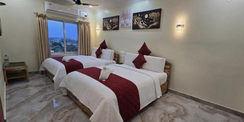 a hotel room with two beds and a window at Hotel KSR Grand in Srikalahasti