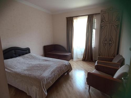 a bedroom with a bed and a chair and a window at Green garden Կանաչ այգի in Ijevan