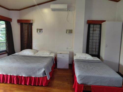 two beds in a room with two windows at Standard - Bluelight Village Hotel in Nadi