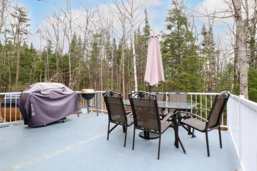 a patio with a table and chairs on a deck at Spa & Sauna - Chalet de l'Ours noir in Notre-Dame-Des-Bois