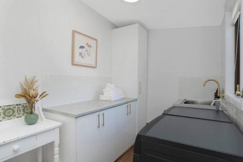 a white kitchen with a sink and a counter at Lava House WIFI central heating cooling CBD in Warrnambool