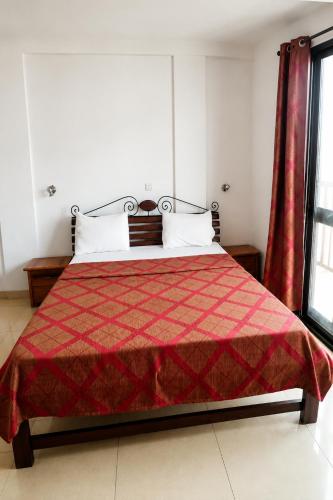 a bedroom with a bed with a red blanket at Akenon Appart Hotel in Ouagadougou