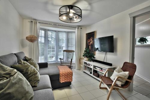 a living room with a couch and a flat screen tv at River & Nature - Nook Richelieu in Henryville