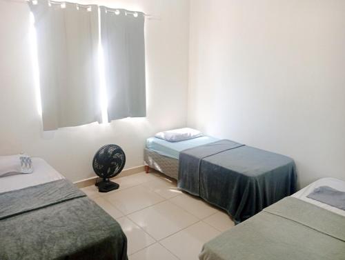 a room with two beds and a fan in it at Casa 2 quartos com garagem in Divinópolis