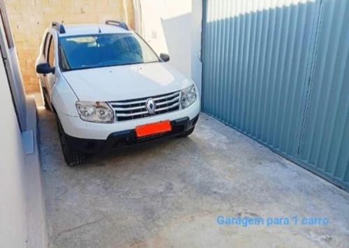 a white car is parked in a garage at Casa 2 quartos com garagem in Divinópolis