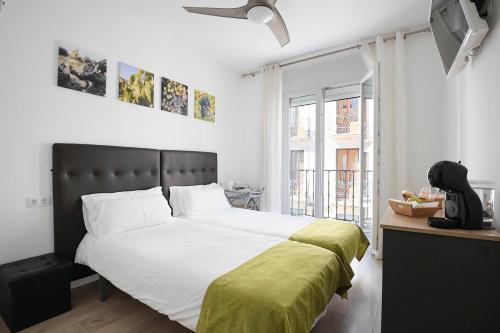 a bedroom with a large bed with a green blanket at Hostal Puente de Hierro in Logroño