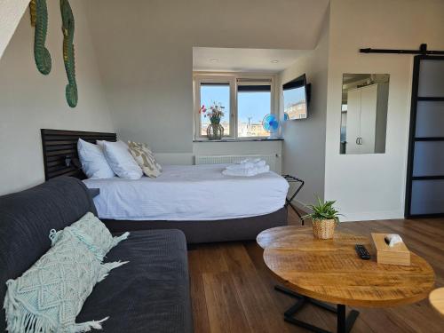 a room with a bed and a table and a couch at Sunnyzandvoort in Zandvoort