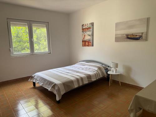 a white bedroom with a bed and two windows at Pink Holiday House Sutomore in Zankovići