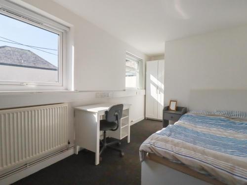 a bedroom with a bed and a desk and a window at Newseal House in St Austell