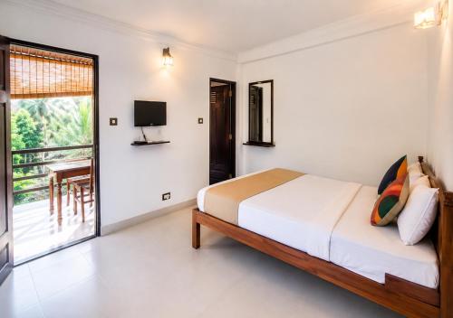 a bedroom with a bed and a television and a balcony at Aditi in Thekkady