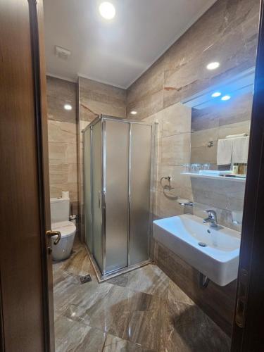a bathroom with a shower and a sink and a toilet at Hotel Argjiro in Gjirokastër