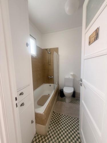 a bathroom with a bath tub and a toilet at Bogage Boutique House in Setúbal