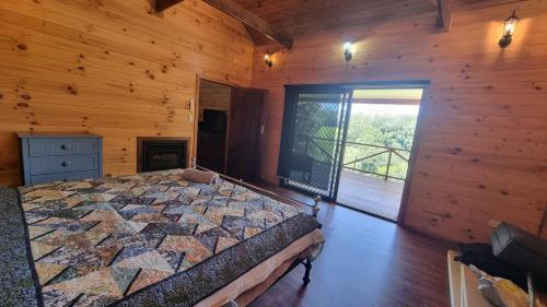 a bedroom with a bed in a wooden cabin at Bellthorpe Retreat in Bellthorpe