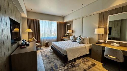 a bedroom with a bed and a desk and a television at Rich Palace Hotel in Surabaya