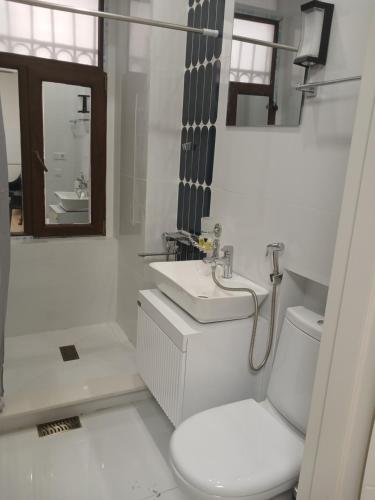 a white bathroom with a toilet and a sink at Hotel White Neptun Georgia Tbilisi in Tbilisi City