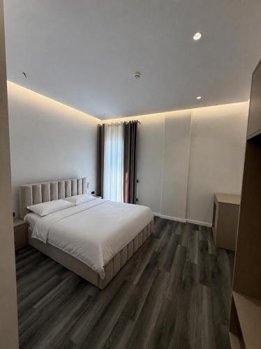 a bedroom with a large white bed and wooden floors at Merlis Hotel in Kusarth