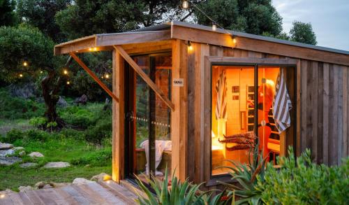 a small wooden house with lights in a garden at The Sanctuary at Bayside Glamping in Marion Bay