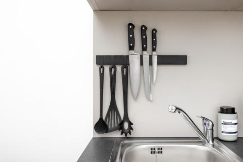 a kitchen counter with utensils hanging on a wall at Global Living Chemnitz Rosenhof in Chemnitz