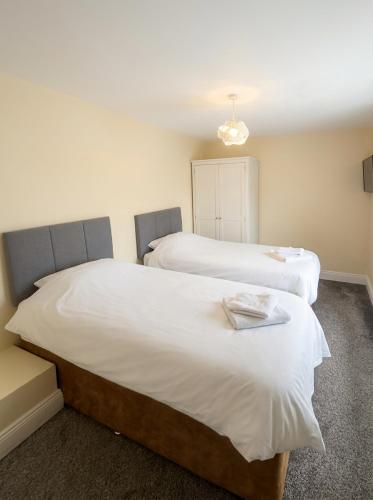 two beds in a room with white sheets at Jennys Bar in Mullagh