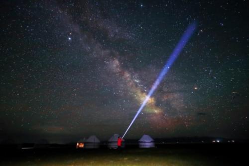 a starry night with tents and a long beam of light at BooGoo yurt camp in Song-Kul