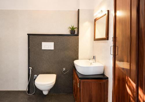 a bathroom with a white toilet and a sink at Aditi in Thekkady