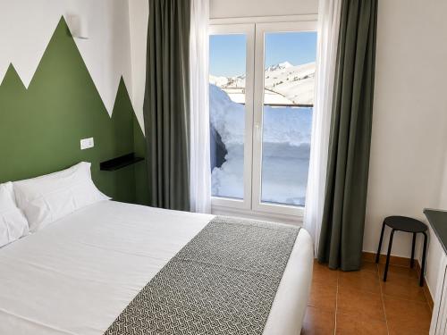 a bedroom with a bed and a window with snow at Hotel Musher in Pas de la Casa