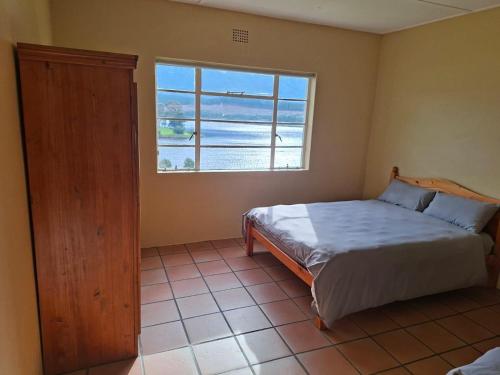 a bedroom with a bed and a large window at Korentepoort Dam in Riversdale