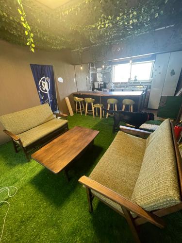 a living room with couches and a table and chairs at ゲストハウスこだまのおうち in Asahikawa