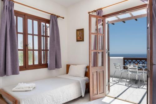 a bedroom with a bed and a balcony with a table at Hotel Albatros in Karpathos