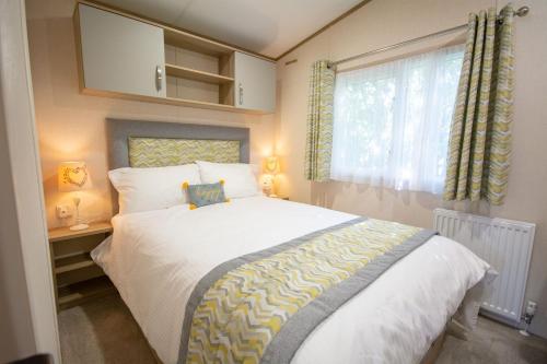 a bedroom with a large white bed with a window at Sea View Lodge in Nefyn