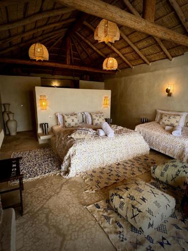 a bedroom with two beds in a room with a ceiling at Agafay Oryx Camp in Aït Mazou