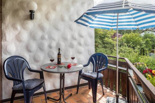 a table with two chairs and an umbrella on a balcony at Friedolin im Bärenhüsli in Titisee-Neustadt