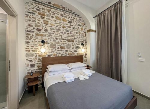 a bedroom with a bed and a brick wall at Ralli 34 ROOMS&APTS in Chios