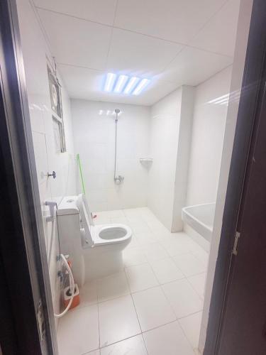 a white bathroom with a toilet and a bath tub at Holiday Abu Dhabi in Abu Dhabi