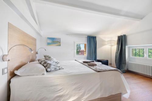 a white bedroom with a large white bed with pillows at Villa Rêve d'Azur in Grasse