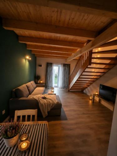 a living room with a couch and a staircase at Domki Osada Kalinowa Nowęcin Łeba Sauna in Łeba