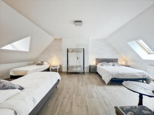 a attic bedroom with two beds and a table at L'Abri Côtier, maison spacieuse avec jardin in Pendé