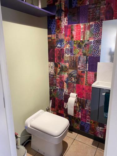 a bathroom with a toilet and a mosaic wall at Maison de campagne in Chièvres
