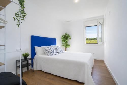 a white bedroom with a bed and a window at Jouvacations Villa Sol La Selva in Vilafant