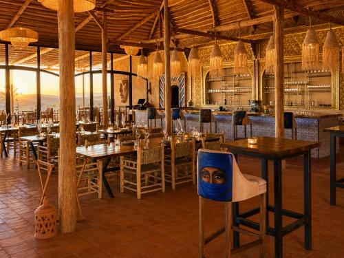 a restaurant with tables and chairs and a chair with a face on it at Agafay Oryx Camp in Aït Mazou