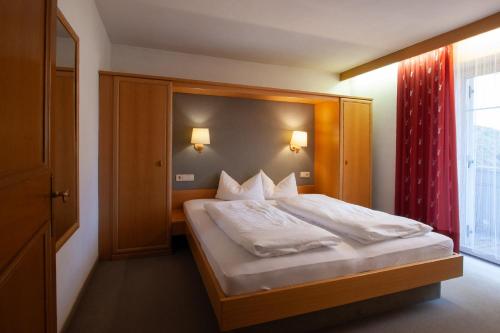 a bedroom with a large bed with a red curtain at Residence Alpenrose in Sesto