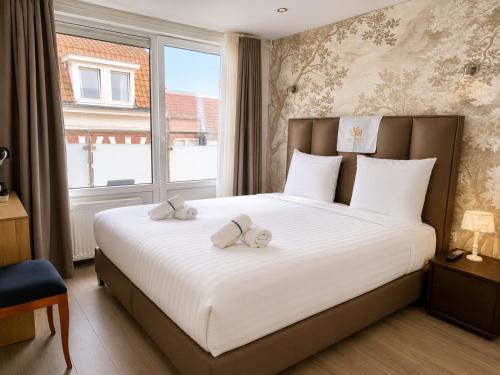 a bedroom with a large white bed with a window at Velocity boutique hotel in Zandvoort