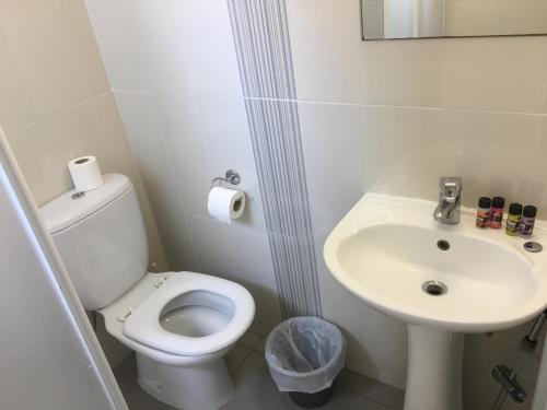 a white bathroom with a toilet and a sink at Mandali Court in Ayia Napa