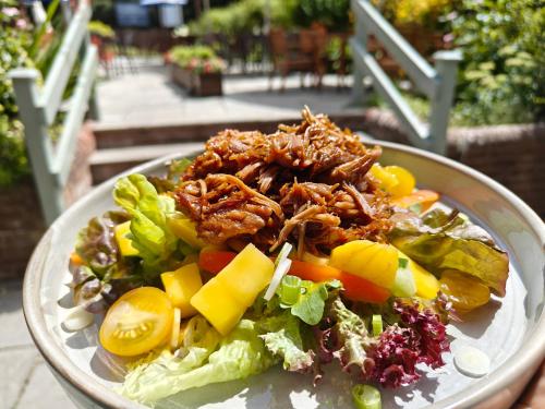a plate of food with meat on top of a salad at The Plough Itchen Abbas in Winchester