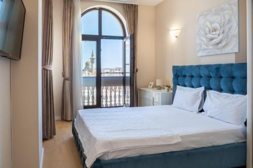 a bedroom with a bed with a blue headboard and a window at Next Apartments Constanta in Constanţa