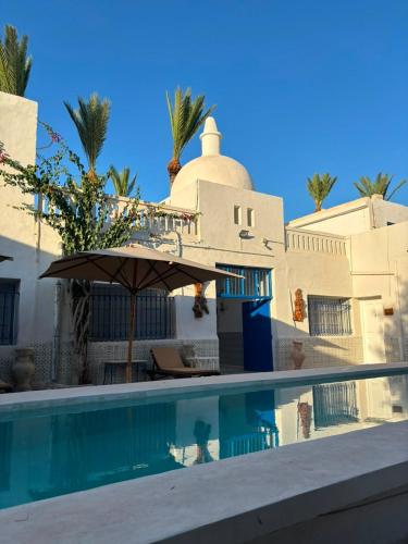 a house with a swimming pool and an umbrella at CoZi at Dar Faiza in Houmt Souk