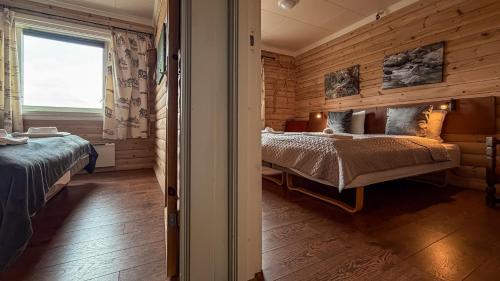 a bedroom with two beds in a room with wooden walls at Terråk Gjestegård in Terråk