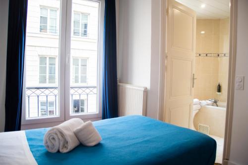 a bedroom with two towels on a bed with a window at Hotel La Louisiane in Paris